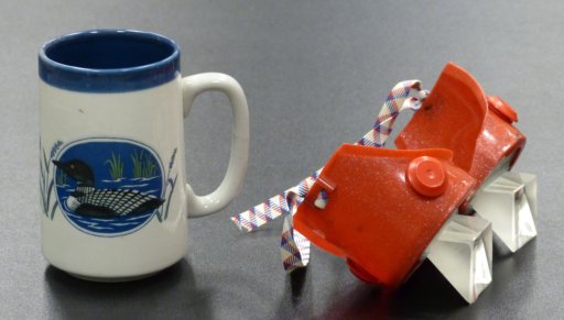 Photograph of a mug and red goggles as seen in day.